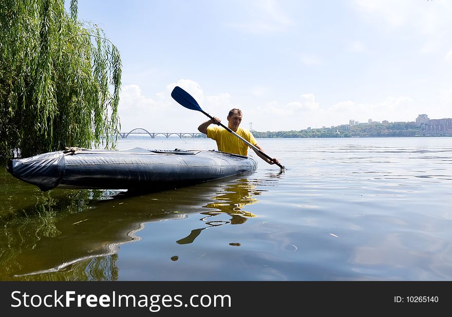 Man in a kayak on the river in shade of trees. Man in a kayak on the river in shade of trees