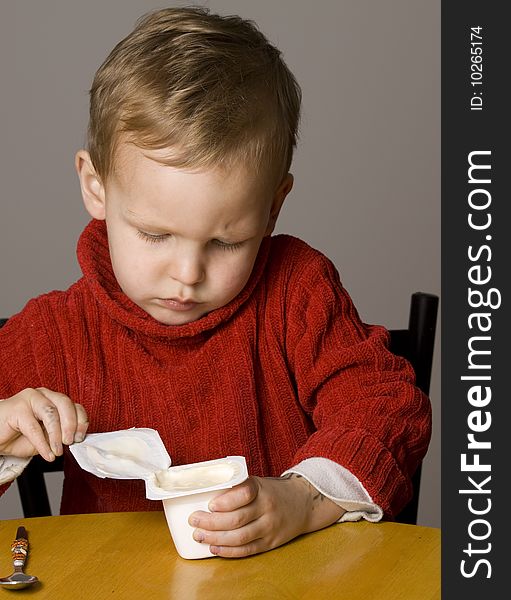 Little Boy opening a yogurt or yoghurt. Little Boy opening a yogurt or yoghurt