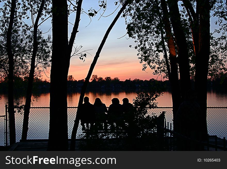 Group of firends sitting watching the sunset at the lake. Group of firends sitting watching the sunset at the lake