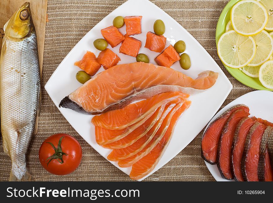 Different kinds of fish with sliced lemon, olives and tomato. Different kinds of fish with sliced lemon, olives and tomato