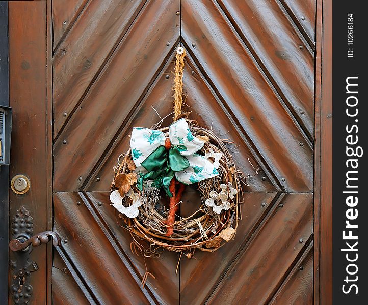 Dry old wreath on brown wooden door closeup