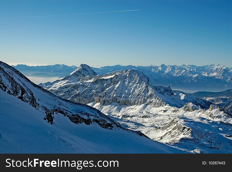Big mountains, winter, blue sky and a flight trail. Big mountains, winter, blue sky and a flight trail