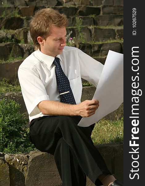 Man reading plans sitting on the steps outdoor