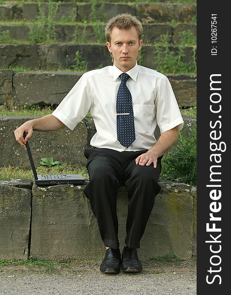 Serious businessman with laptop computer sitting on the steps. Serious businessman with laptop computer sitting on the steps