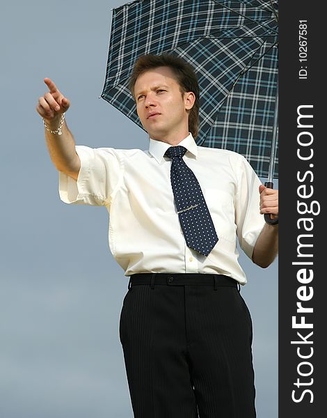 Businessman with umbrella pointing with finger outdoor