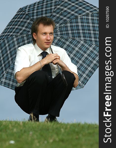 Man with umbrella sitting on the grass