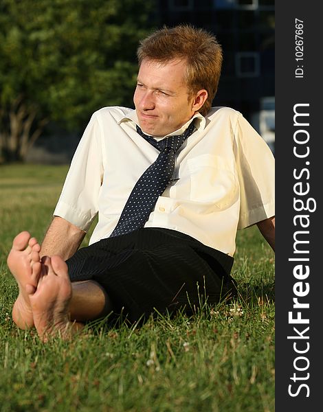 Businessman relaxing in a city park barefoot. Businessman relaxing in a city park barefoot