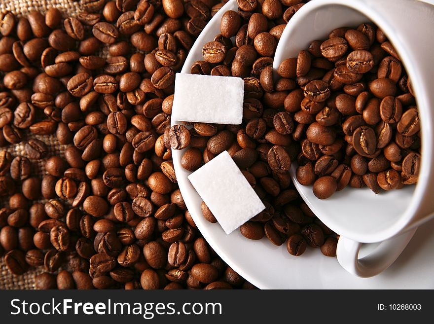 Beans of coffee with sugar, cup and dish