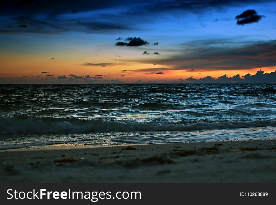 A colorful sunset creates the backdrop for the waves rolling into the shore at the beach. A colorful sunset creates the backdrop for the waves rolling into the shore at the beach.