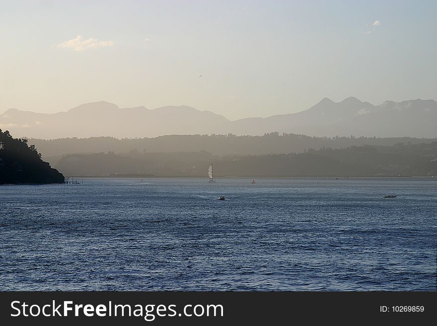 Yacht and motorboat in the Knysna estuary with mountains in the background