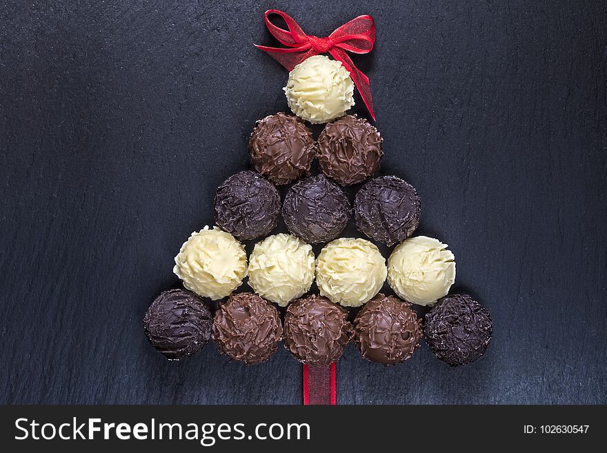 Chocolate truffles shaped Christmas tree on black stone table top view. Chocolate truffles shaped Christmas tree on black stone table top view.