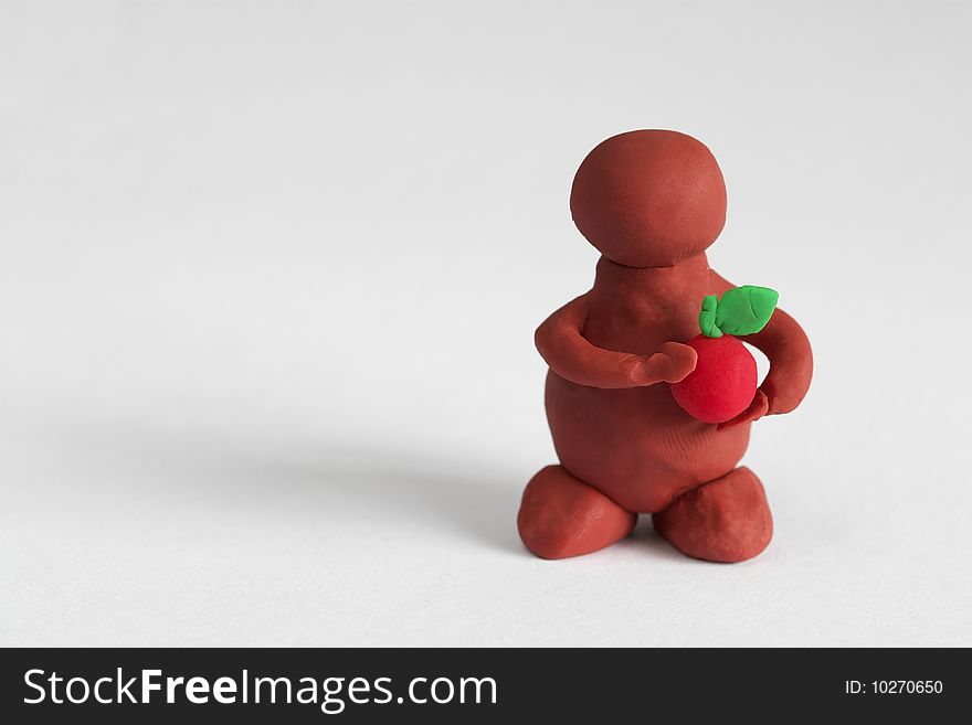 Plasticine man keeping a red apple over grey background