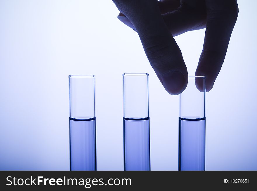 Hand pulling test tube out of test tube rack. Hand pulling test tube out of test tube rack