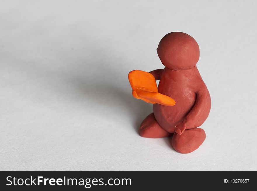 Plasticine man reading the book over grey background