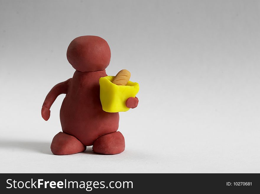 Plasticine customer keeping a bag with a bread over grey background. Plasticine customer keeping a bag with a bread over grey background