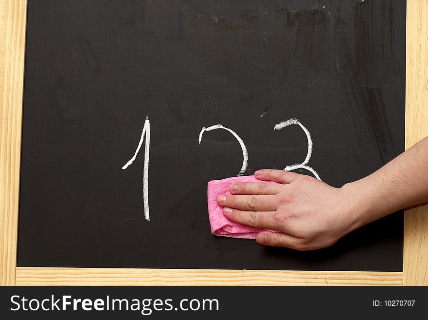 Wiping digits from the blackboard with pink wipe. Wiping digits from the blackboard with pink wipe