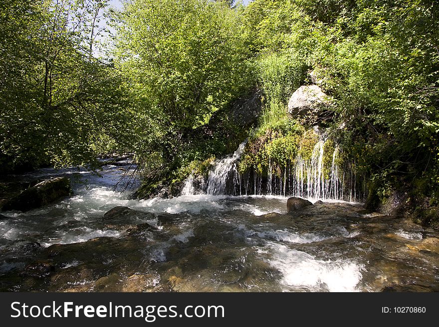 Mountain River in the summer with blue sky and trees in the background. Mountain River in the summer with blue sky and trees in the background