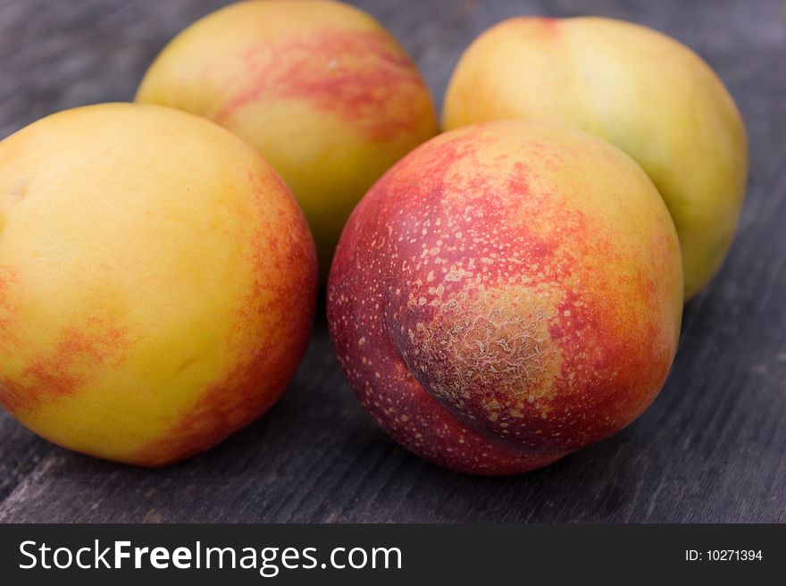 Four ripe nectarines on wooden table