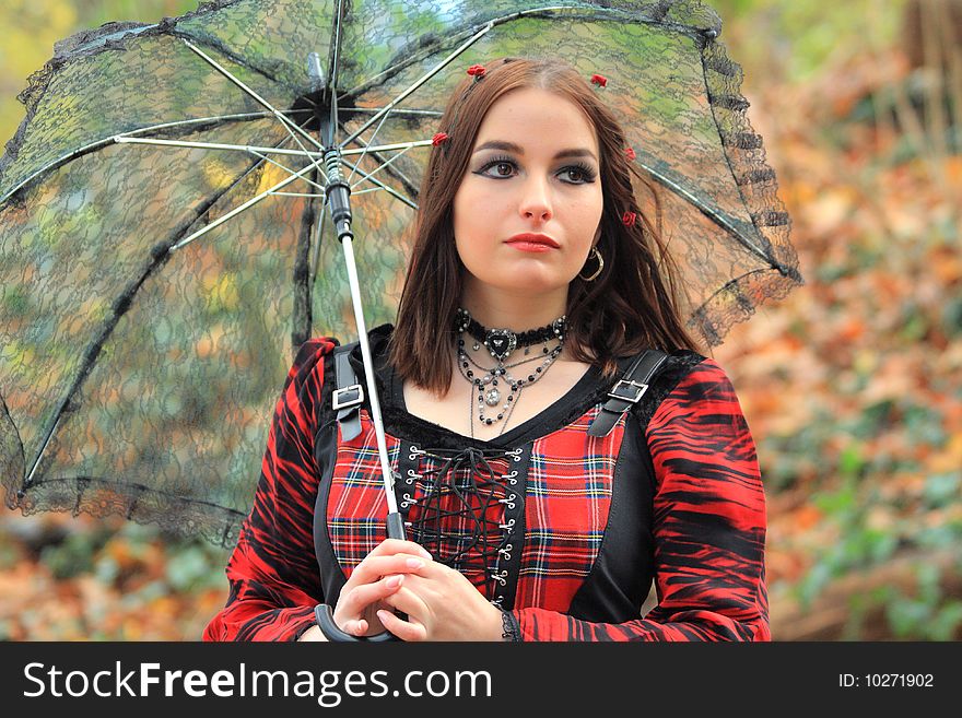 Gothic model with brown eye's and red roses in her hair under an umbrella. Outside photography. Gothic model with brown eye's and red roses in her hair under an umbrella. Outside photography.