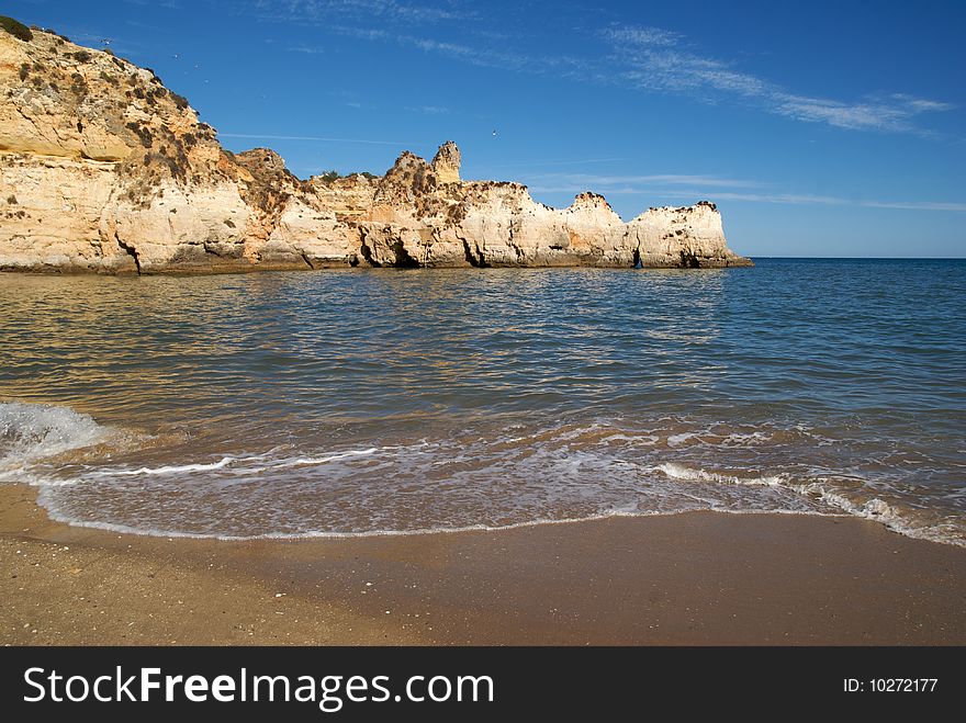 A beach in the Algarve with a rock formation in the background. A beach in the Algarve with a rock formation in the background.