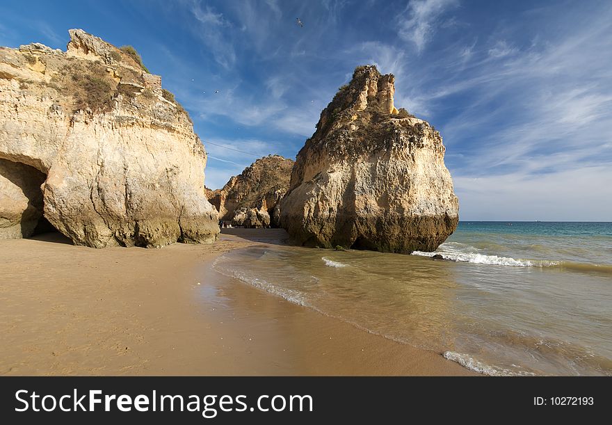 A beach in the Algarve with some rock formations and a cloudy sky. A beach in the Algarve with some rock formations and a cloudy sky.