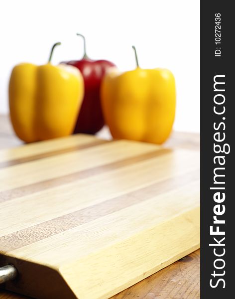 Wooden chopping board and capsicum chilli peppers in the background