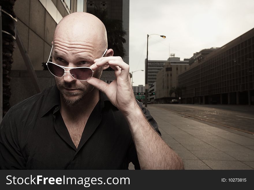 Bald man removing his shades and looking away