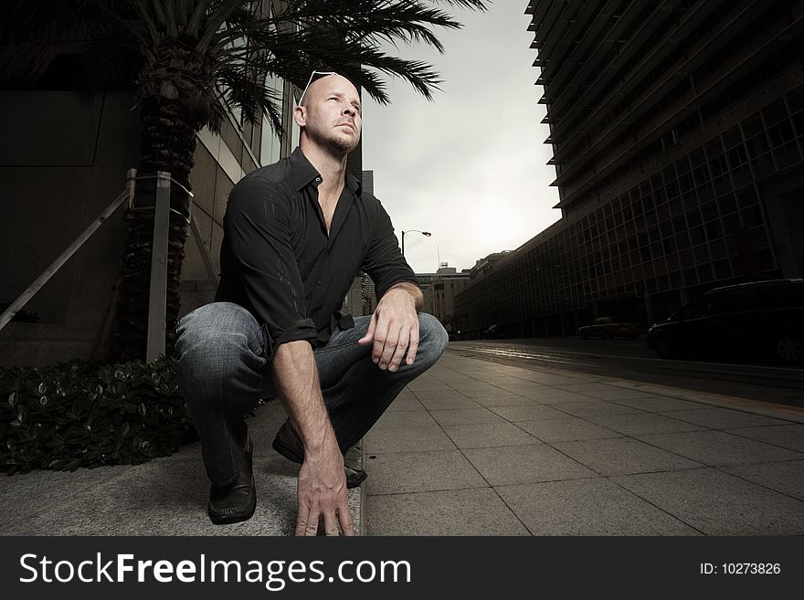 Man squatting on a ledge. Man squatting on a ledge