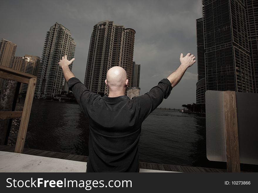 Man facing buildings with his arms extended outward. Man facing buildings with his arms extended outward