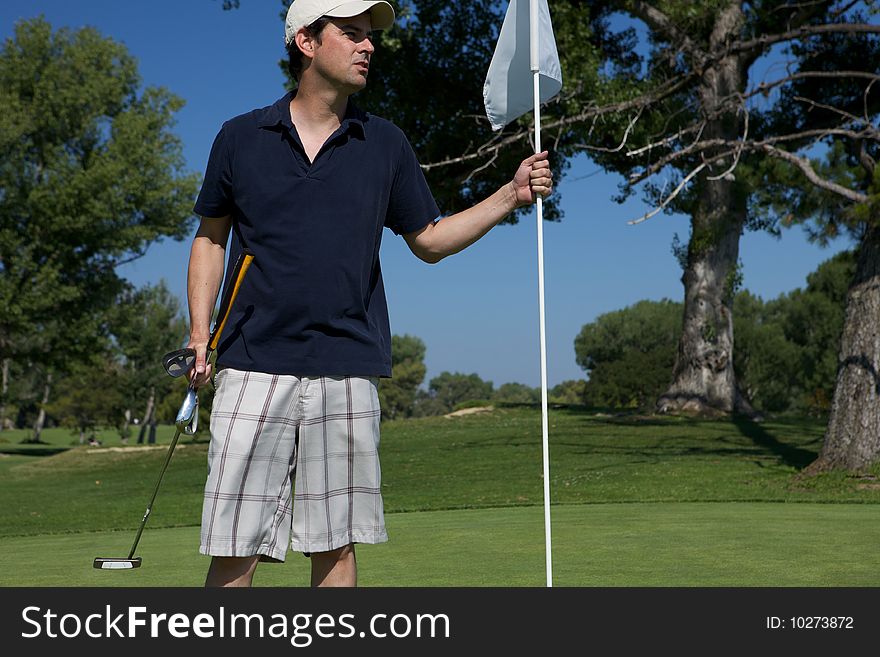 A Man golfing swinging his club toward the tee