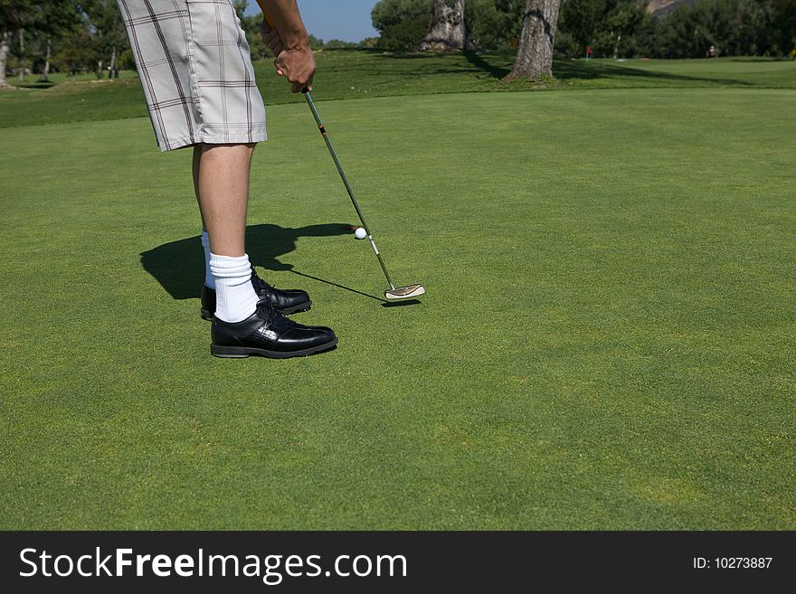 A Man golfing swinging his club toward the tee