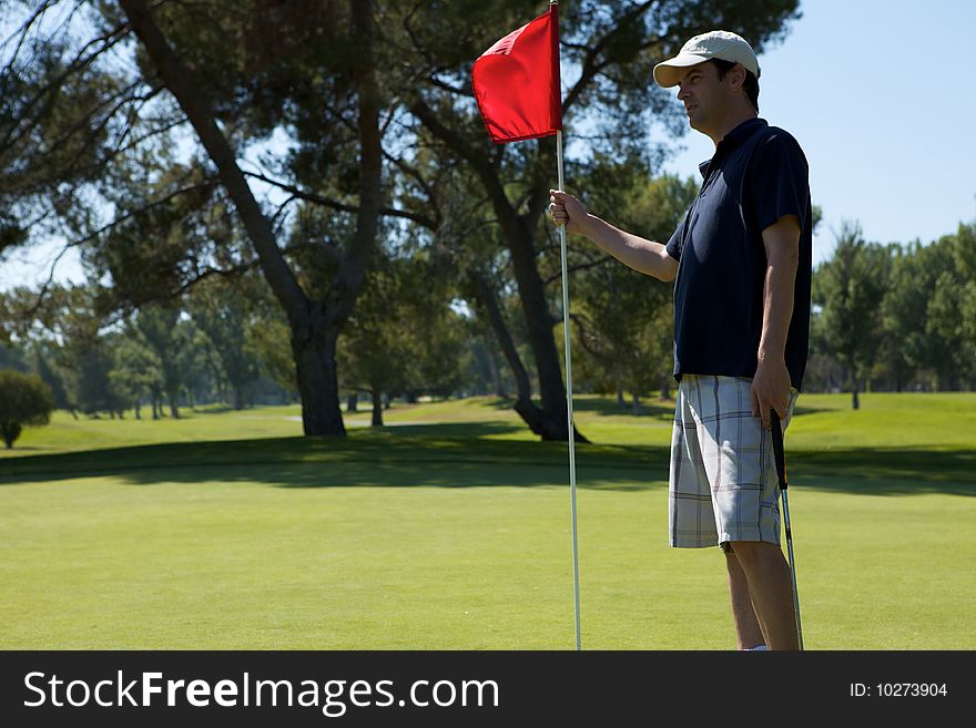 A Man golfing swinging his club toward the tee