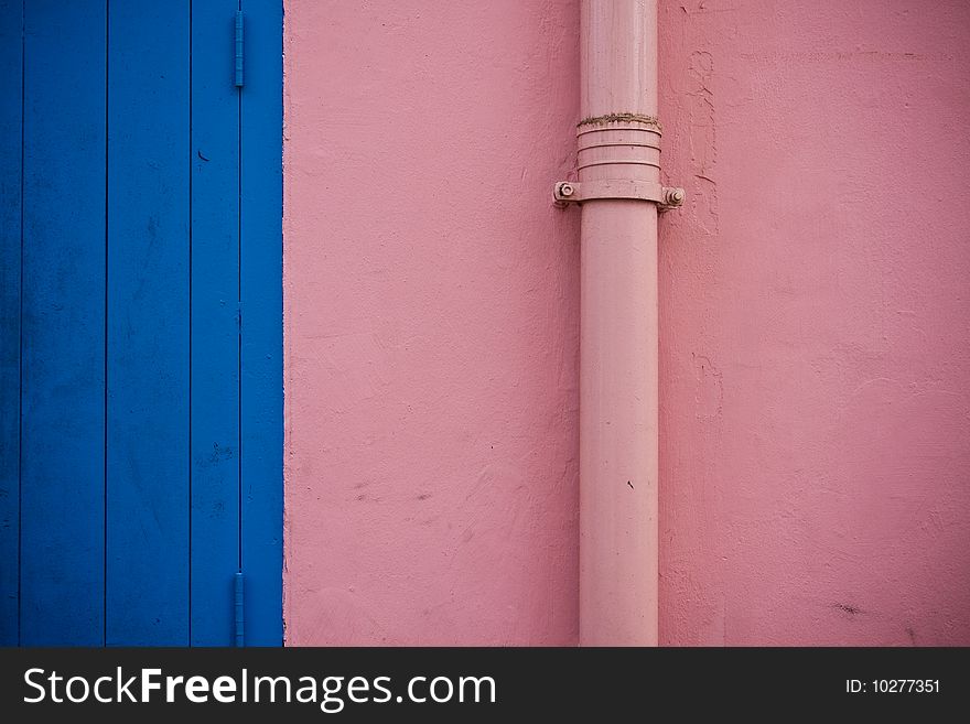 Rain gutter in front of a colorful wall.