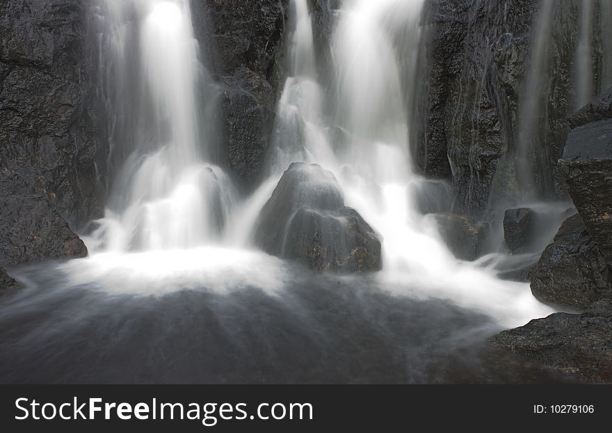 Waterfall with white water and dark rocks in Norway