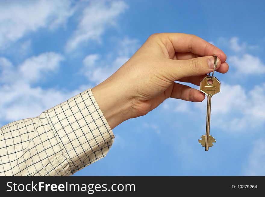 Hand holding a key over sky and clouds backgound