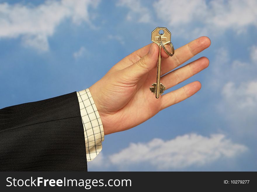 Hand holding a key over sky and clouds backgound