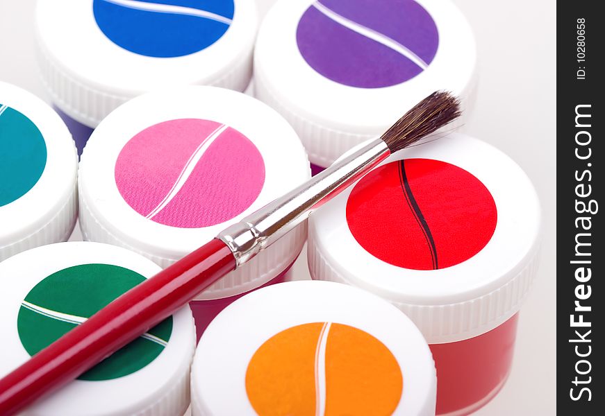 Group of colorful paint cans with brush to background