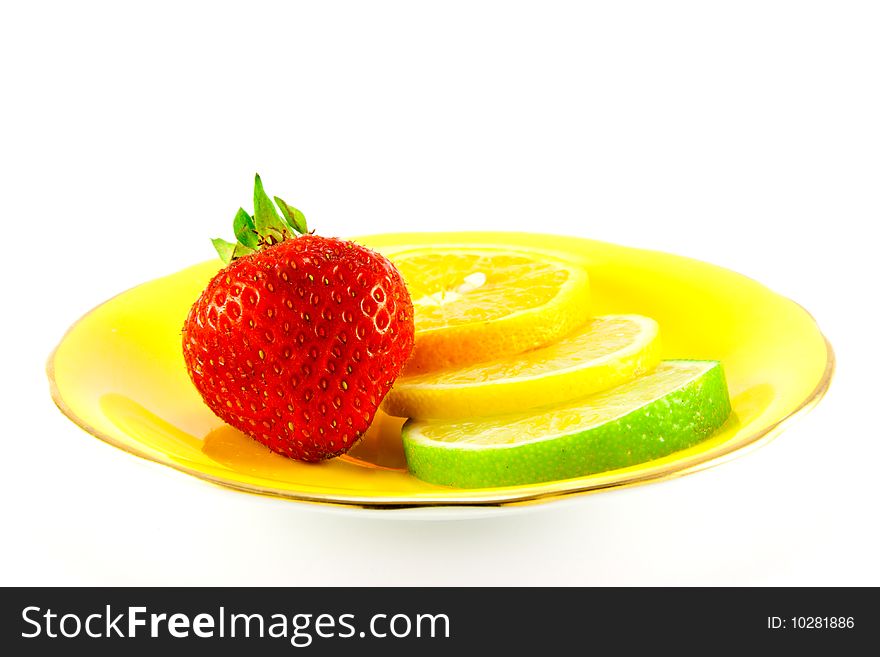 Slice of lemon, lime and orange with a red juicy strawberry on a fancy yellow plate with a white background. Slice of lemon, lime and orange with a red juicy strawberry on a fancy yellow plate with a white background