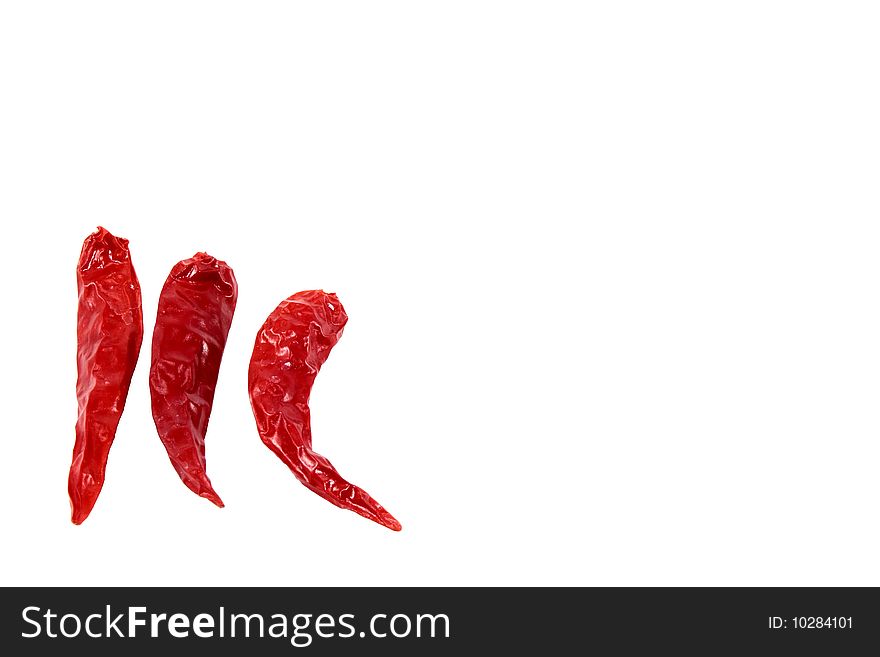 Three dried hot peppers isolated off-center against a white background. Three dried hot peppers isolated off-center against a white background