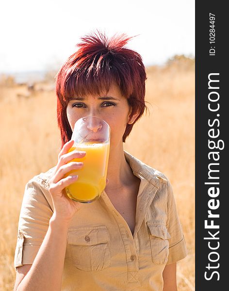 WOMAN DRINKING VITAMIN C ORANGE JUICE OUTDOORS IN NATURE. WOMAN DRINKING VITAMIN C ORANGE JUICE OUTDOORS IN NATURE