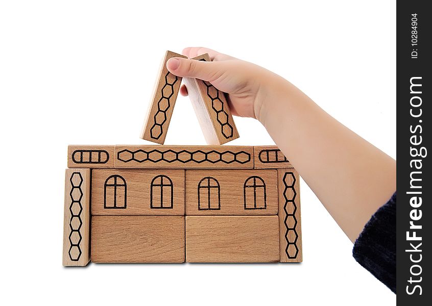 Children's hand building house from wooden toy blocks isolated on white. Children's hand building house from wooden toy blocks isolated on white