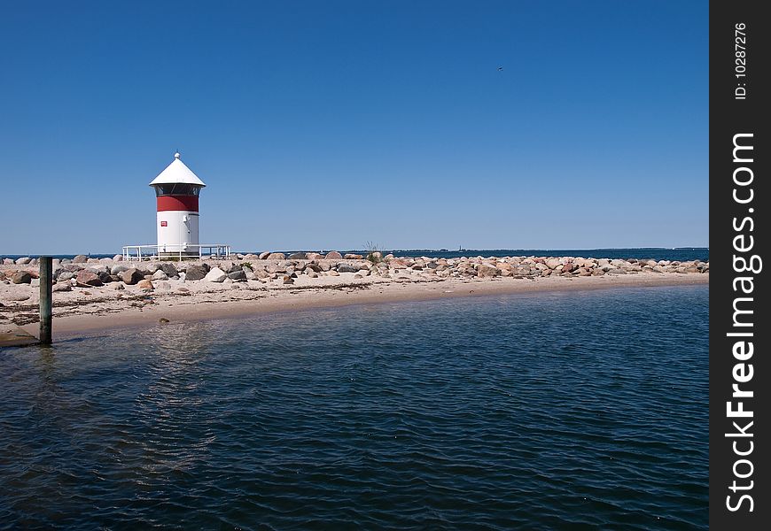 Small red and white lighthouse by the sea