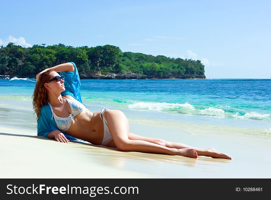 Beautiful brunette young girl relaxing on the sand beach on Bali island in Indonesia. Beautiful brunette young girl relaxing on the sand beach on Bali island in Indonesia