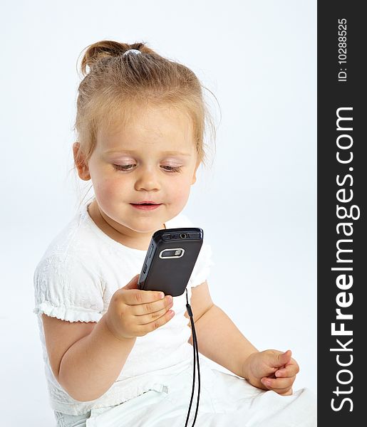 Little girl with mobile phone on gray background