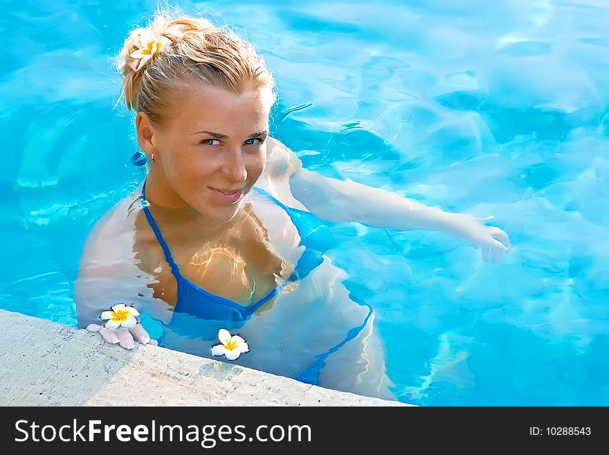 Beautiful blonde girl in hotel swimming pool with flower in long hair. Beautiful blonde girl in hotel swimming pool with flower in long hair