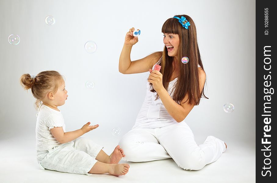 Little girl and her mother blowing bubbles