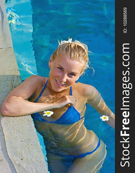 Beautiful blonde girl in hotel swimming pool with flowers. Beautiful blonde girl in hotel swimming pool with flowers