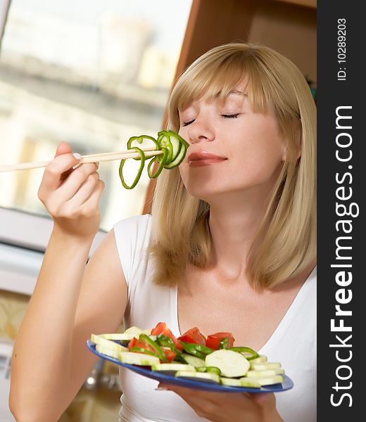 The young woman eats green salad. The young woman eats green salad