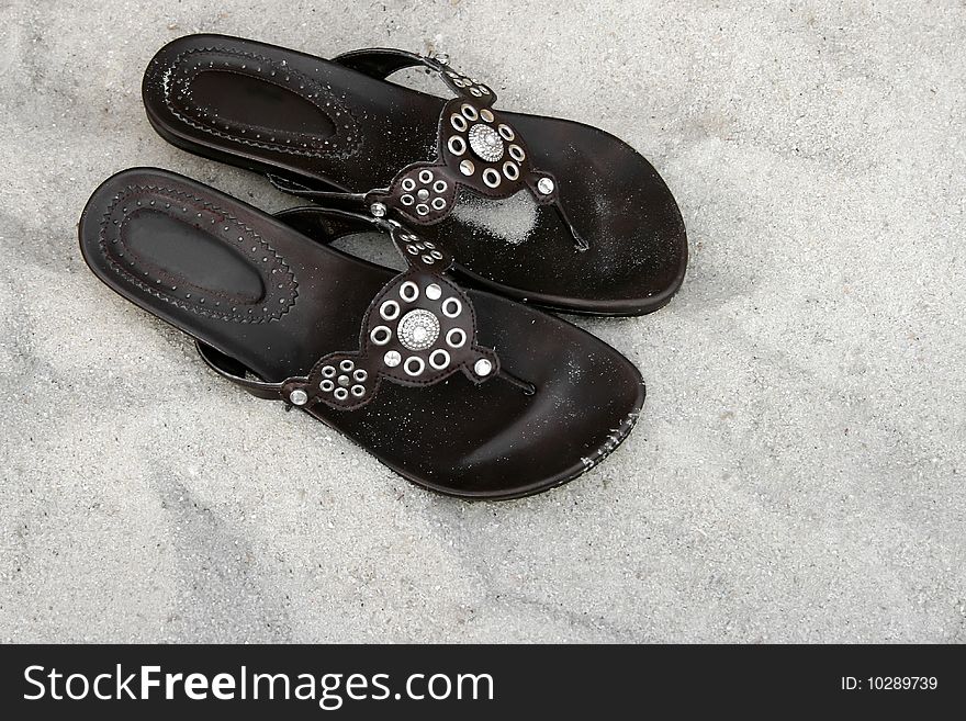 Pair of brown shoes with silver pattern design on the sand. Pair of brown shoes with silver pattern design on the sand