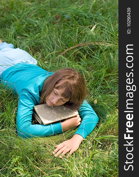 Young girl sleeping on a meadow with a book. Young girl sleeping on a meadow with a book